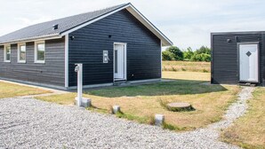 En modern byggnad med en mörk fasad, ett sluttande tak och en liten, intilliggande byggnad med en vit dörr.