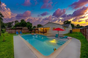 A backyard with a swimming pool, lounge chairs, and a small house. - Newly updated Home with Pool, Patio, BBQ! 5BR 3BA 10mi from Downtown Sleeps 15 (Houston)