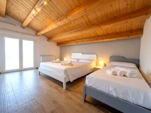 A room with two beds, wooden ceiling beams, and a large window. - Apartment in Villa with garden and private terrace (Kaukana)
