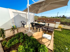 A patio area with a grill, outdoor seating, and a garden. - Apartment in Villa with garden and private terrace (Kaukana)