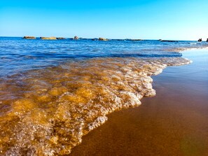 A beach with clear water, a sandy shore, and distant rocky formations. - Apartment in Villa with garden and private terrace (Kaukana)