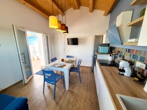 A modern kitchen with a dining area, wooden ceiling, and a TV mounted on the wall. - Apartment in Villa with garden and private terrace (Kaukana)