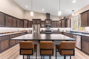 A modern kitchen with dark wood cabinets, stainless steel appliances, and a central island with seating.