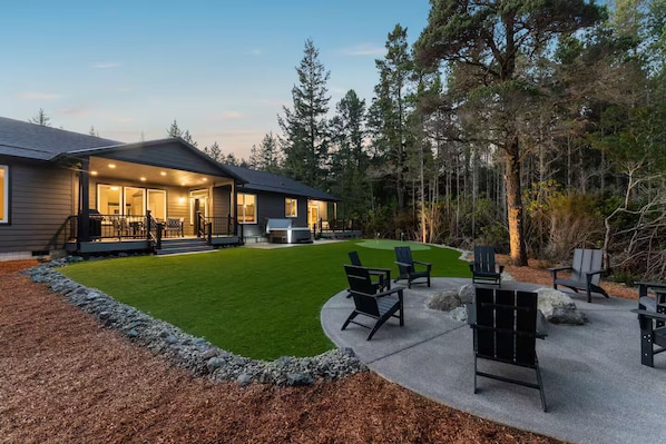 A house with a patio, outdoor seating, and a well-maintained lawn.