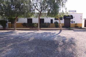 Un edificio con un letrero que dice 'Los Palmillos H' y un estacionamiento de grava.