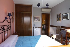 Habitació d'hotel amb llit, escriptori, cadira, armari i petita cuina.