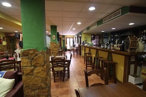 Un restaurante con pilares de piedra, mesas de madera y una zona de bar.