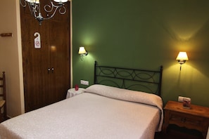 Un dormitorio con una cama, dos lámparas de pared, un armario de madera y una mesita de noche con lámpara.