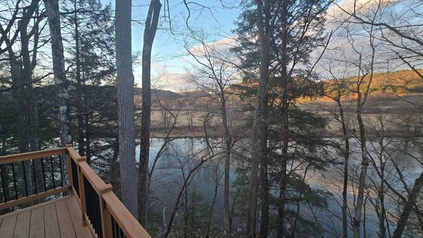 A wooden deck overlooking a forested area with a lake. - Rose's  RV Camping  - Private 2300' Riverfront Site on the West Branch Delaware (Starlight)