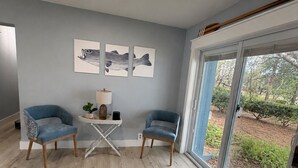 A modern living room with two blue armchairs, a small table with a lamp, and artwork on the wall. - Modern Lakefront Getaway ,Family Friendly & Relaxing (Keystone Heights)