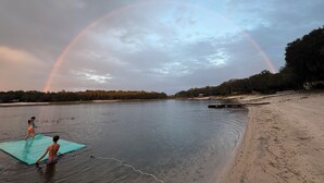 A beach with a rainbow, calm water, and a person in the water. - Modern Lakefront Getaway ,Family Friendly & Relaxing (Keystone Heights)