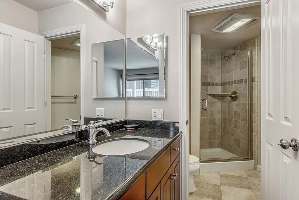 A bathroom with a large mirror, a sink, and a shower area.