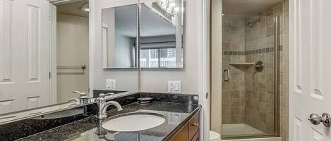 A bathroom with a large mirror, a sink, and a shower area.