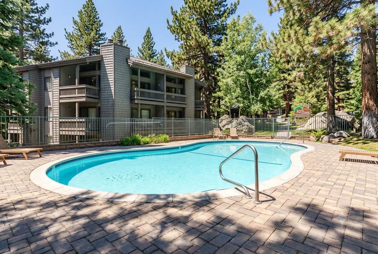 A pool area with a rectangular pool, a wooden deck, and a building with balconies.