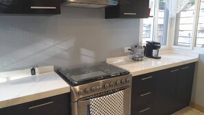Una cocina con estufa, cafetera y armarios.