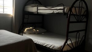 Habitación con literas, ventana, aire acondicionado y piso de baldosas.