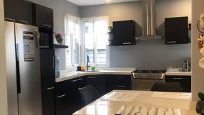 Una cocina moderna con refrigerador, estufa, microondas y ventilador de techo.