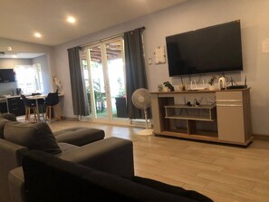 A living room with a sofa, a TV, a fan, and a sliding glass door leading to a patio. - Peaceful Escape From City Life (Las Isletas)