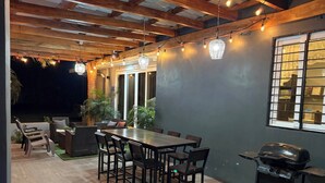 Un patio al aire libre con una mesa de comedor, sillas y una parrilla.