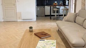 Een moderne woonkamer met een bank, een salontafel en een keuken op de achtergrond.