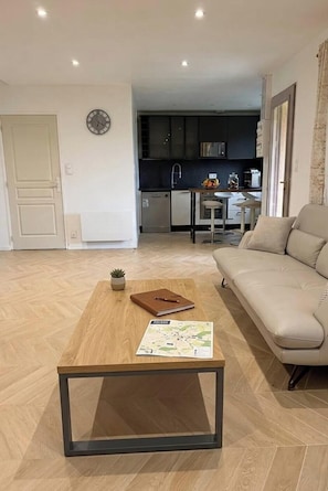 Ein modernes Wohnzimmer mit einer Couch, einem Couchtisch und einer Küche im Hintergrund.