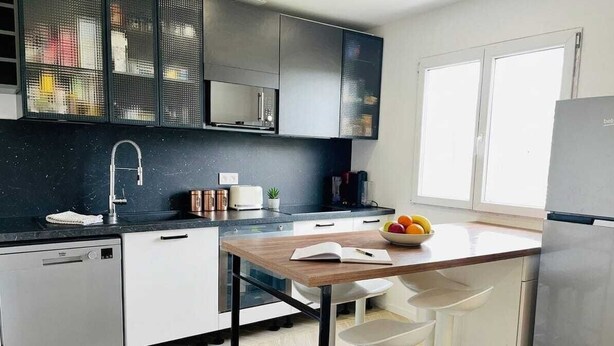 Een moderne keuken met een vaatwasser, witte kasten, een houten eiland en een koelkast.