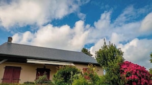Een huis met een schuin dak, schoorsteen en een raam met luiken.