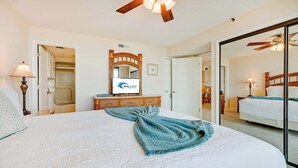 Ein Hotelzimmer mit einem großen Bett, einem Spiegel, einem Fernseher und einer Holzkommode.