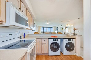 Eine Küche mit Mikrowelle, Backofen, Waschmaschine und Holzschränken.