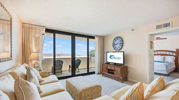 Ein Hotelzimmer mit Balkon, Fernseher, Bett und einer Couch.