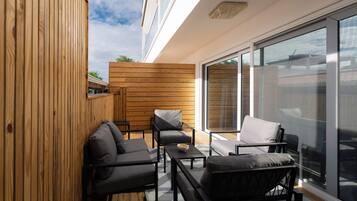 Un área de estar exterior moderna con paneles de madera, un ventanal y vista al cielo.