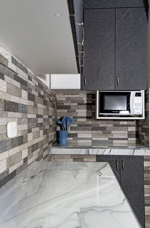 A kitchen with a microwave, dark cabinets, and a tiled backsplash. - Cozy  2-bedroom apartment in vibrant Cuzco 8 minutes walking to Town Center (Cuzco)