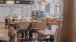 Ravintolassa on raidalliset tuolit ja pöydät, riippuvalaisimet ja peili.
