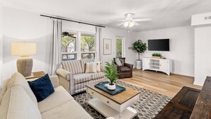 Una sala de estar con sofá, sillón, mesa de centro y televisor.
