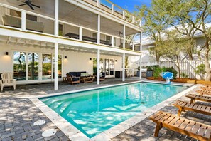 Ein zweistöckiges Haus mit Swimmingpool, Außenbereich mit Sitzgelegenheiten und einer überdachten Terrasse.