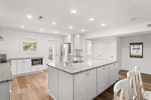 A modern kitchen with white cabinetry, granite countertops, and a large island. - Heated Pool, Lake Dock & Beach – 4BR Duplex Side B (Inlet Beach)