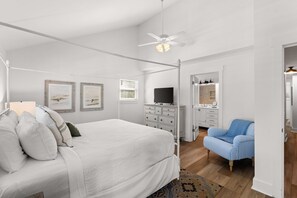 Ein Schlafzimmer mit Himmelbett, Fernseher, Kommode und Stuhl.