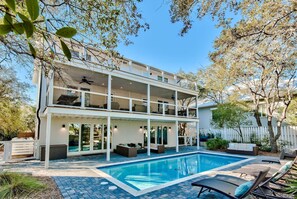 Ein zweistöckiges Haus mit Pool, Sitzgelegenheiten im Freien und einer überdachten Terrasse.