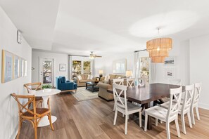 Ein geräumiges Wohnzimmer mit Esstisch, Stühlen, Sofas und Deckenventilator.