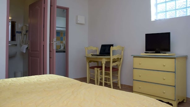 Makuuhuoneessa on sänky, työpöytä kannettavalla tietokoneella, televisio, joka on sijoitettu lipaston päälle, ja ikkuna.