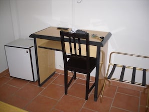 A small room with a desk, a chair, a radiator, and a small fridge. - Courtinn Aqua (Avignon)