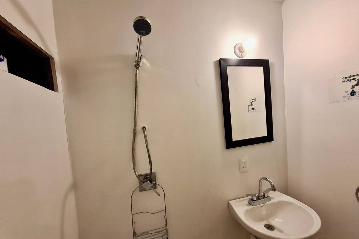 Casa de banho com chuveiro, lavatório e espelho.