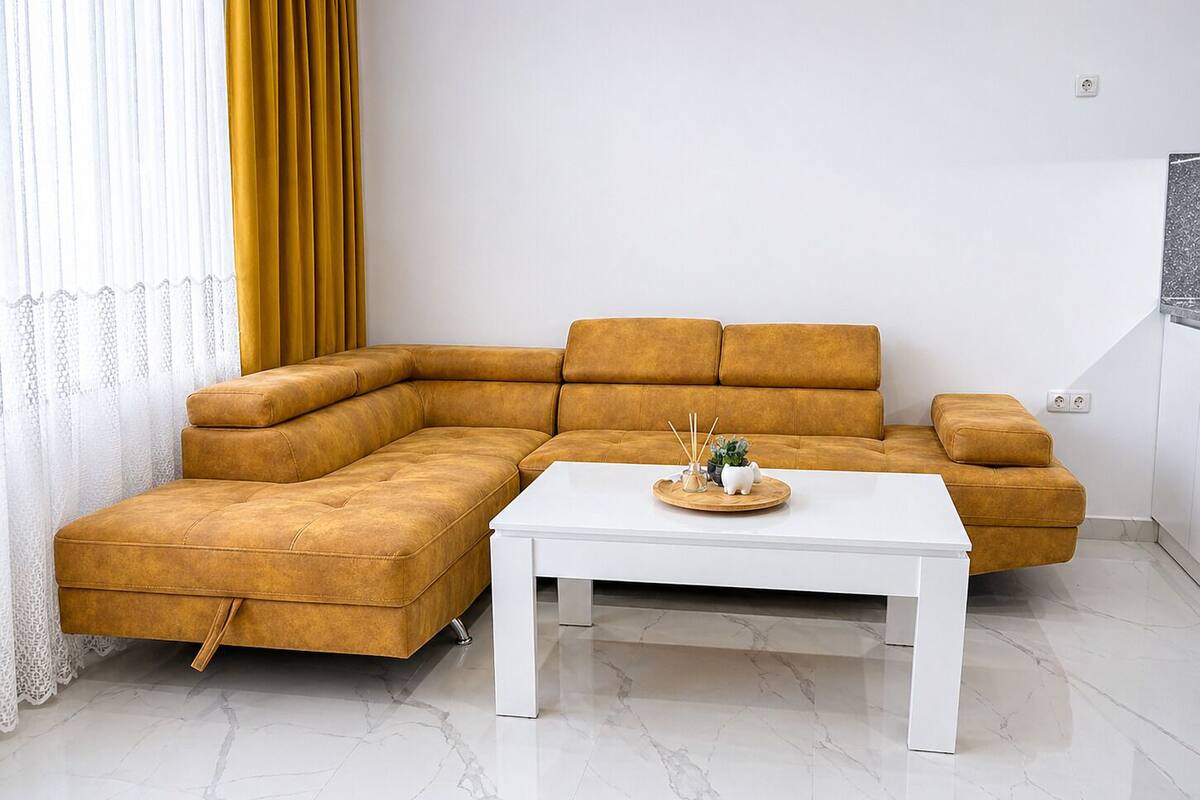Ein modernes Wohnzimmer mit einem Ecksofa, einem weißen Couchtisch und einer dekorativen Ablagefläche.