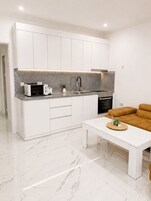 Una cocina moderna con armarios blancos, microondas integrado, lavamanos y estufa.