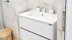 Un baño con lavamanos blanco, espejo y paredes de mármol.