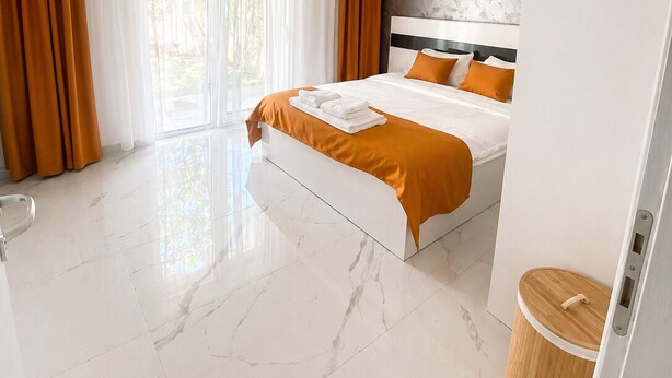 Una habitación de hotel moderna con una cama grande, un baño con inodoro y lavamanos, y vistas al exterior.