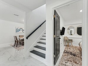 Eine Treppe führt zu einem Essbereich mit Marmorboden, einem Esstisch mit Stühlen und einem Teppich.