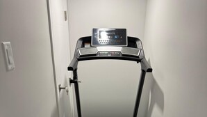 A ProForm treadmill in a narrow hallway with a door on one side and a light switch on the wall. - New 1BR Suite in Aspen Ridge, Saskatoon for a home away from home experience. (Saskatoon)