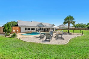 A house with a swimming pool, outdoor seating, and a fenced yard.