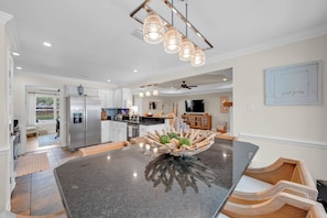 A modern kitchen with a large island, stainless steel appliances, and a dining area with a unique wooden centerpiece.